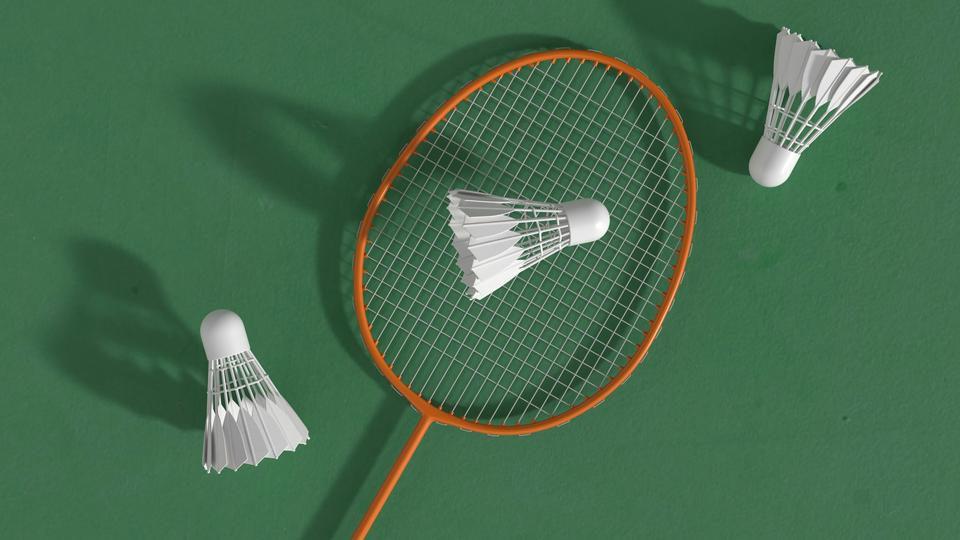A badminton racket with 3 shuttles on a plain green background