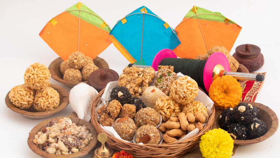 Traditional Lohri celebration display featuring colorful kites, baskets of Indian sweets (laddoos), peanuts, jaggery, popcorn, sugarcane, and festive decorations symbolizing the harvest festival of Lohri.