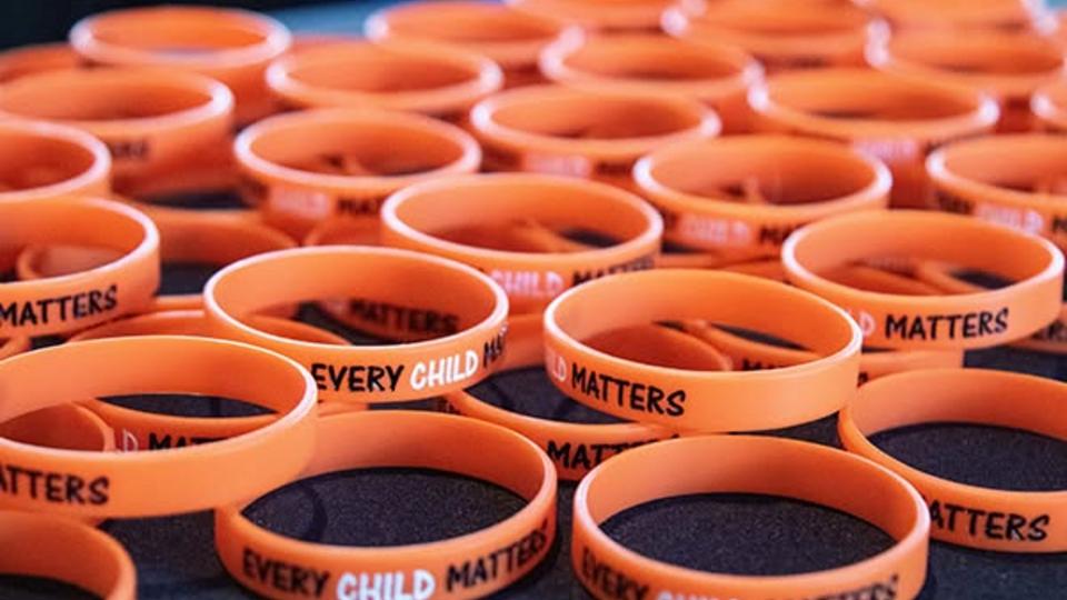 Orange wrist bands that say Every Child Matters