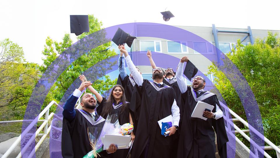 students in caps and gowns throw their caps in the air
