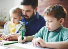 Man helping two small children with colouring.