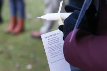 A vigil attendee holds a candle with a tag that states: December 6th, National Day of Remembrance and Action on Violence Against Women.