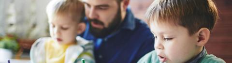 A man looking at something with two small children. 