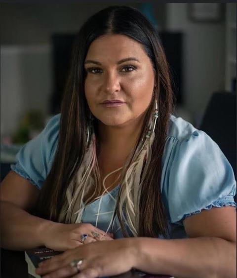 Brandi Morin wears a light blue shirt and stares directly at the camera