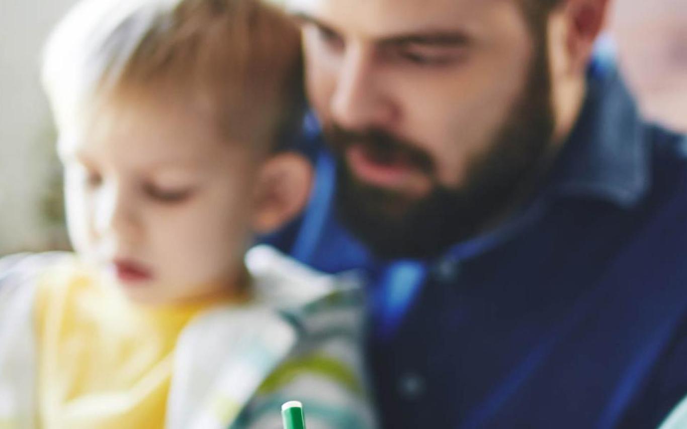 A man looking at something with two small children. 