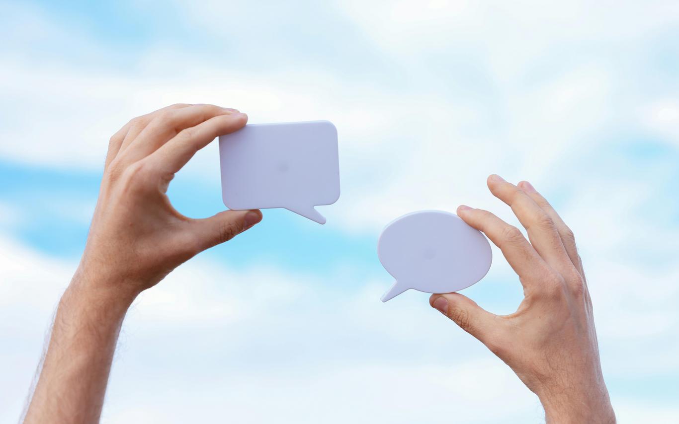 Two hands hold up talk bubbles