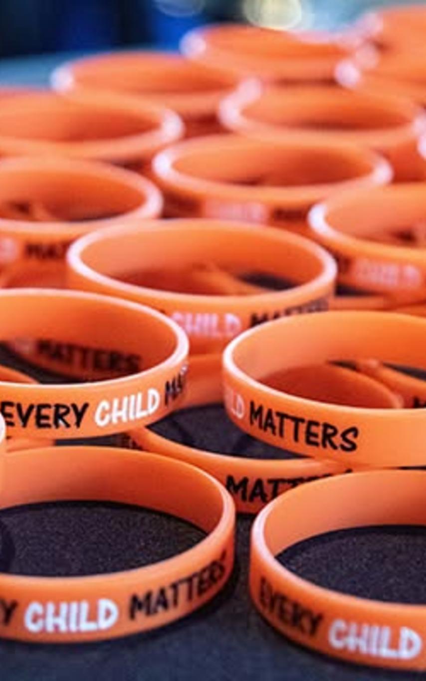 Orange wrist bands that say Every Child Matters