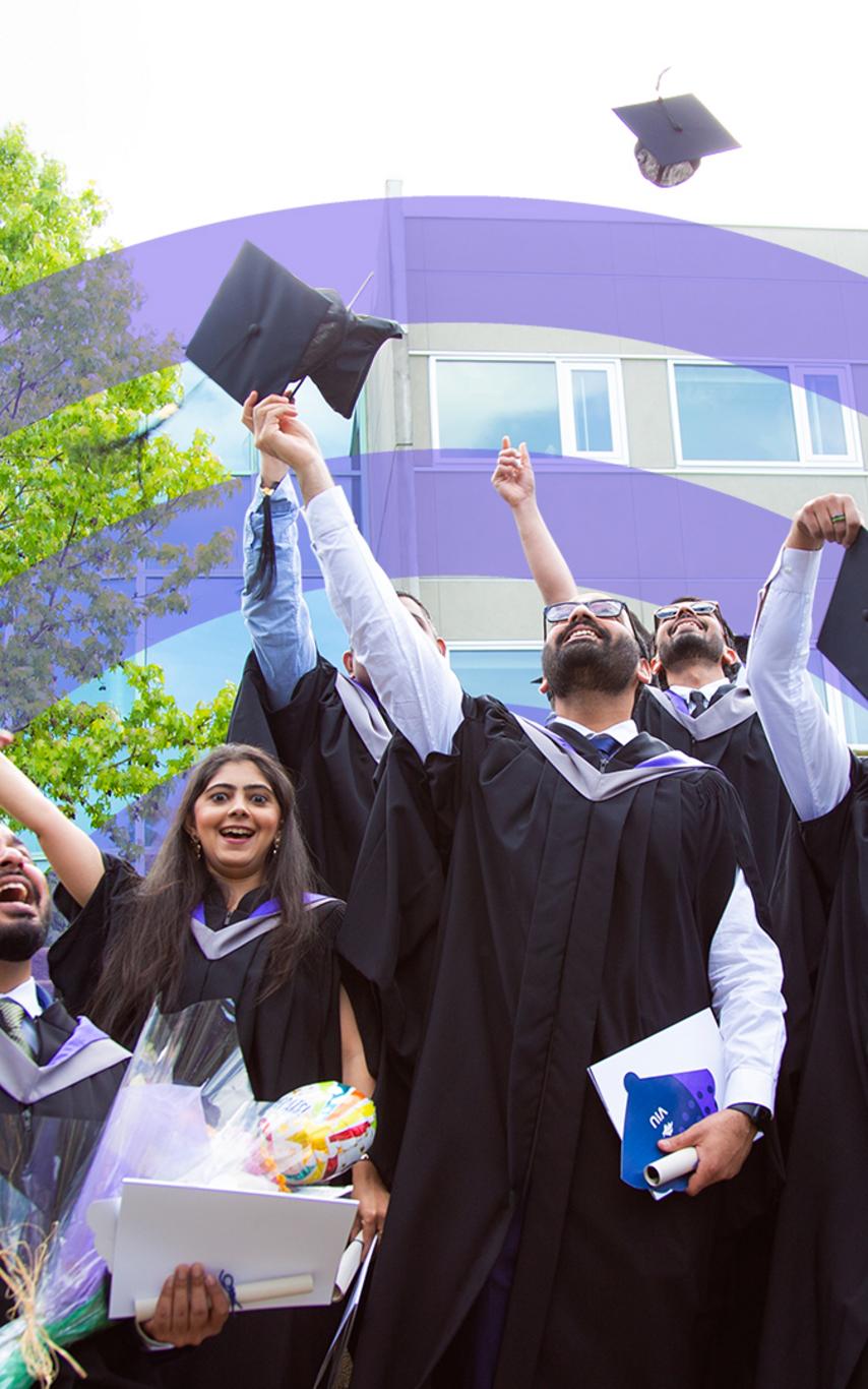 students in caps and gowns throw their caps in the air